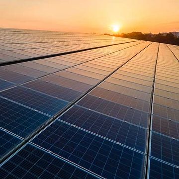 Blaue Photovoltaik-Solarpaneele auf dem Dach des Gebäudes montiert, um bei Sonnenuntergang sauberen, ökologischen Strom zu erzeugen