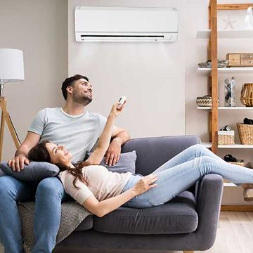 Glückliche Frau hält Klimaanlagen-Fernbedienung in der Hand